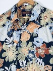 Black Hawaiian shirt with orange, blue, and green floral print, front pocket, and “Tori Richard” label on hanger.