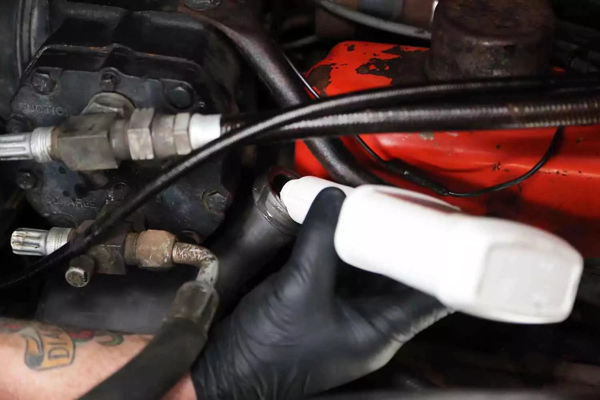 A mechanic fills the power steering pump reservoir with fresh power steering fluid.