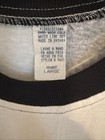 White vintage T-shirt with black trim, size large, featuring a sewn neck label reading “100% Cotton Hand Wash Dry Made in U.S.A.”