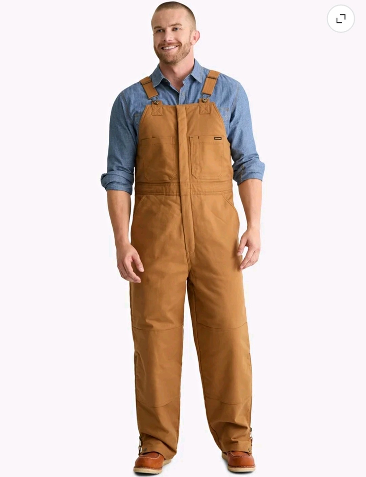 Brahma men’s insulated canvas bib overalls in brown cotton with front pocket and blue denim shirt.