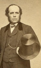MAN POSED STANDING HOLDING TOP HAT, PHOTO ALBUM IN TABLE. CDV. FITCHBURG, MASS. 