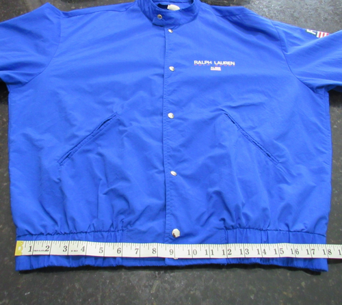 Blue Vtg 90s Polo Sport Ralph Lauren jacket with white snap buttons, pointed collar, and visible “Vtg 90s Polo Sport” text.