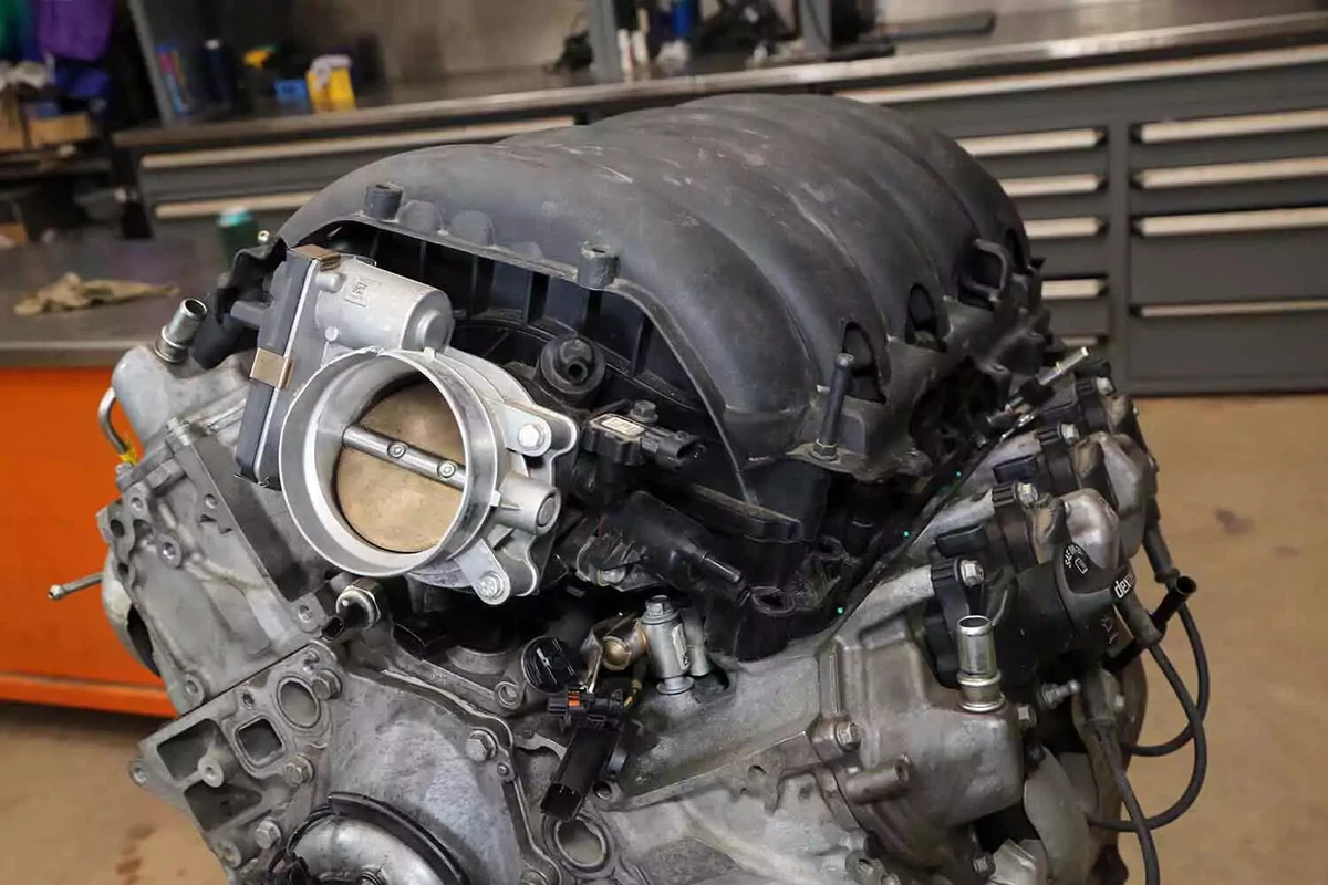 A domestic V-8 engine with a plastic intake manifold on an engine stand in a workshop.