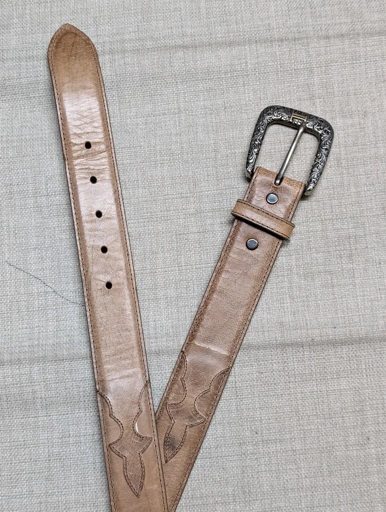 Tan leather western belt with an engraved silver buckle.