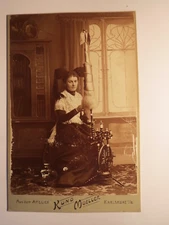 Karlsruhe I. B. - Young woman sitting on spinning wheel in costume - backdrop / cab