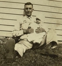 1940s Man Holding Baby Portrait Sitting Against Siding Happy Family Moment