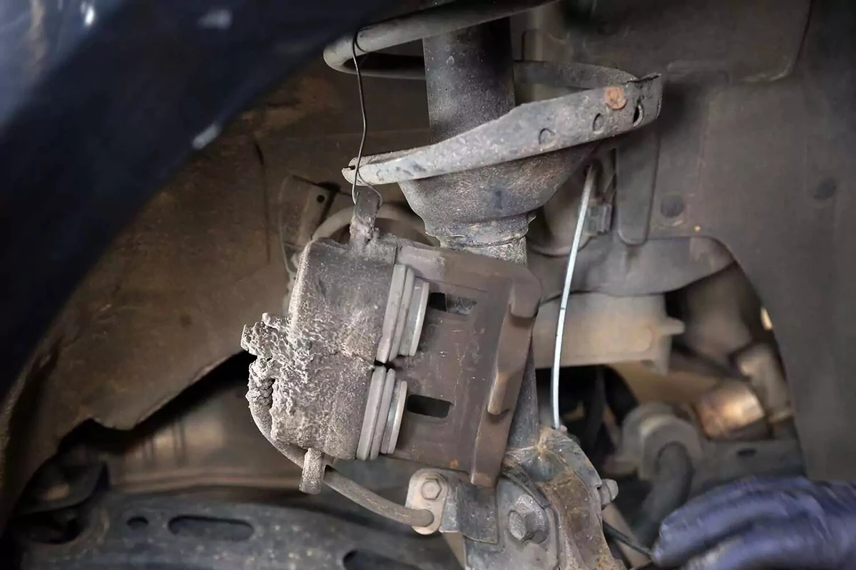 Brake caliper hanging from baling wire in the wheel well.