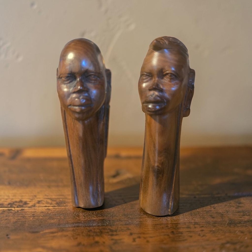 A signed pair of hand-carved African tribal head sculptures — the kind of shelf statement that sparks a conversation every single time.
