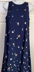 Navy blue sleeveless midi dress with small white floral print, displayed on mannequin against light wood background.