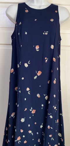Navy blue sleeveless midi dress with small white floral print, displayed on mannequin against light wood background.