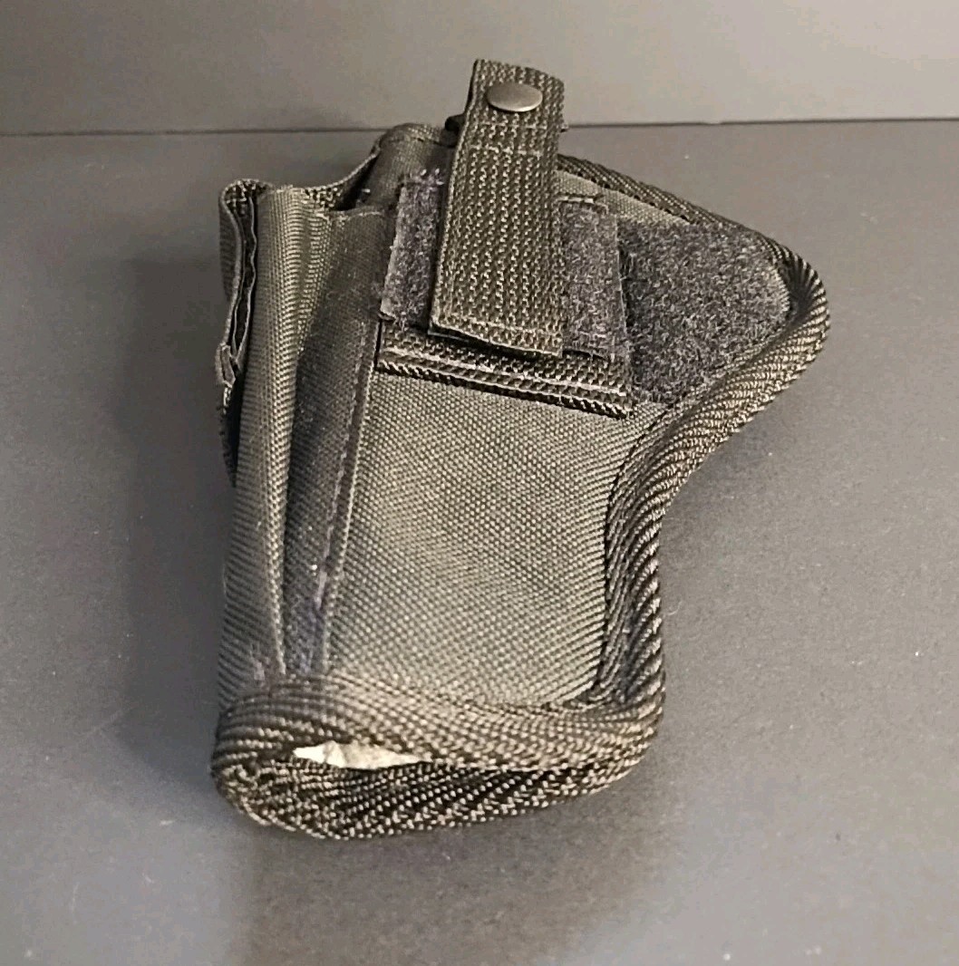 Black nylon, USA made, ambidextrous IWB holster with flap pocket and silver snap closure on a gray surface.