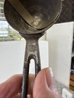 Worn antique silver metal ice cream scoop with visible scratches and textured handle, made in USA around 1900.