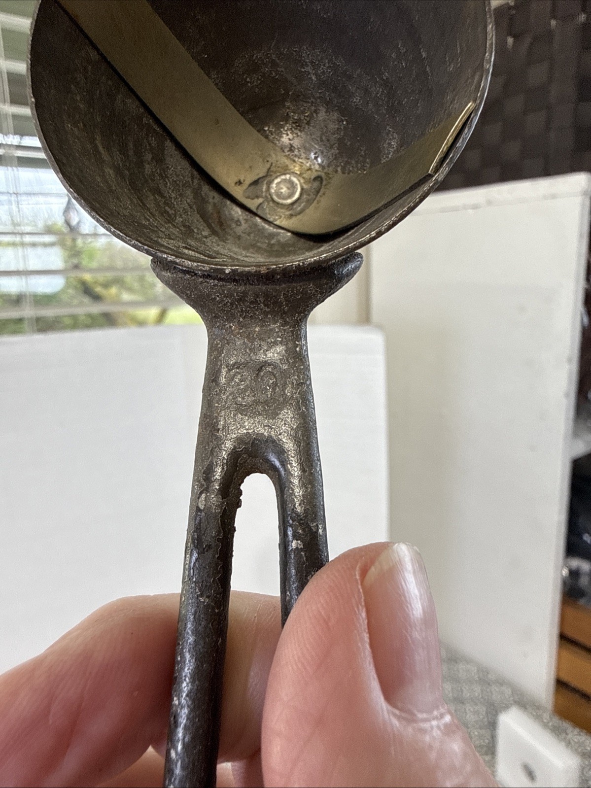 Worn antique silver metal ice cream scoop with visible scratches and textured handle, made in USA around 1900.