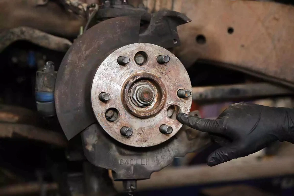 A mechanic points out one of the three wheel hub bolts.