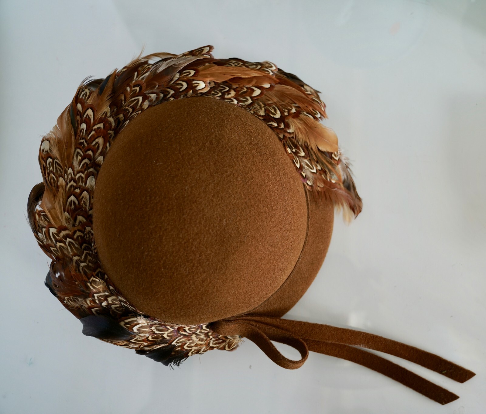 Brown hat with 100% wool EXCELLO, pheasant feathers, and tan ribbon on white background.