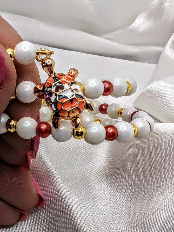 Brazalete de porcelana con cuentas de oro de 18 quilates y perlas con dije de tortuga marina Foto 2 de 3