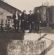Four Individuals Standing on Industrial Tank Early 20th Century Camaraderie
