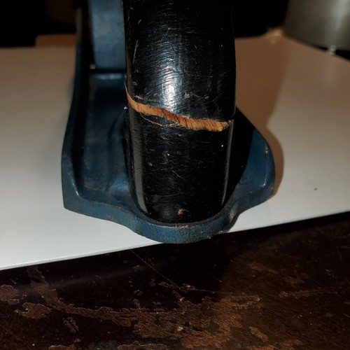 Close-up of worn black wood hand plane with visible grain pattern and small circular crackle on the smooth bottom.