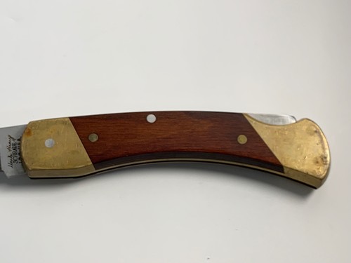 Vintage Schrade Uncle Henry LB 7 lockback with brass handle, wooden grip, and “Made in U.S.A.” engraving on side.