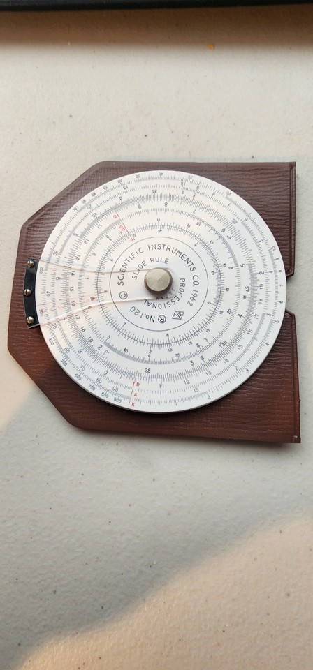 A 1962 circular slide rule from Scientific Instruments Co. — the round form factor makes it look like a pocket watch crossed with a calculator.