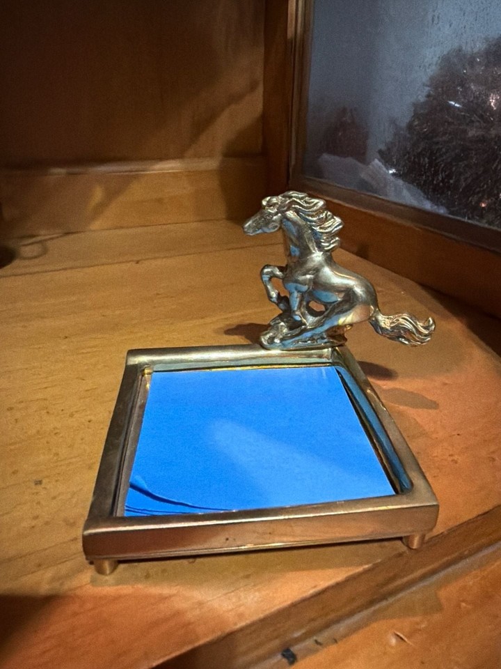 A rearing brass horse doubles as a sticky note holder — equal parts equestrian art and practical desk tool.