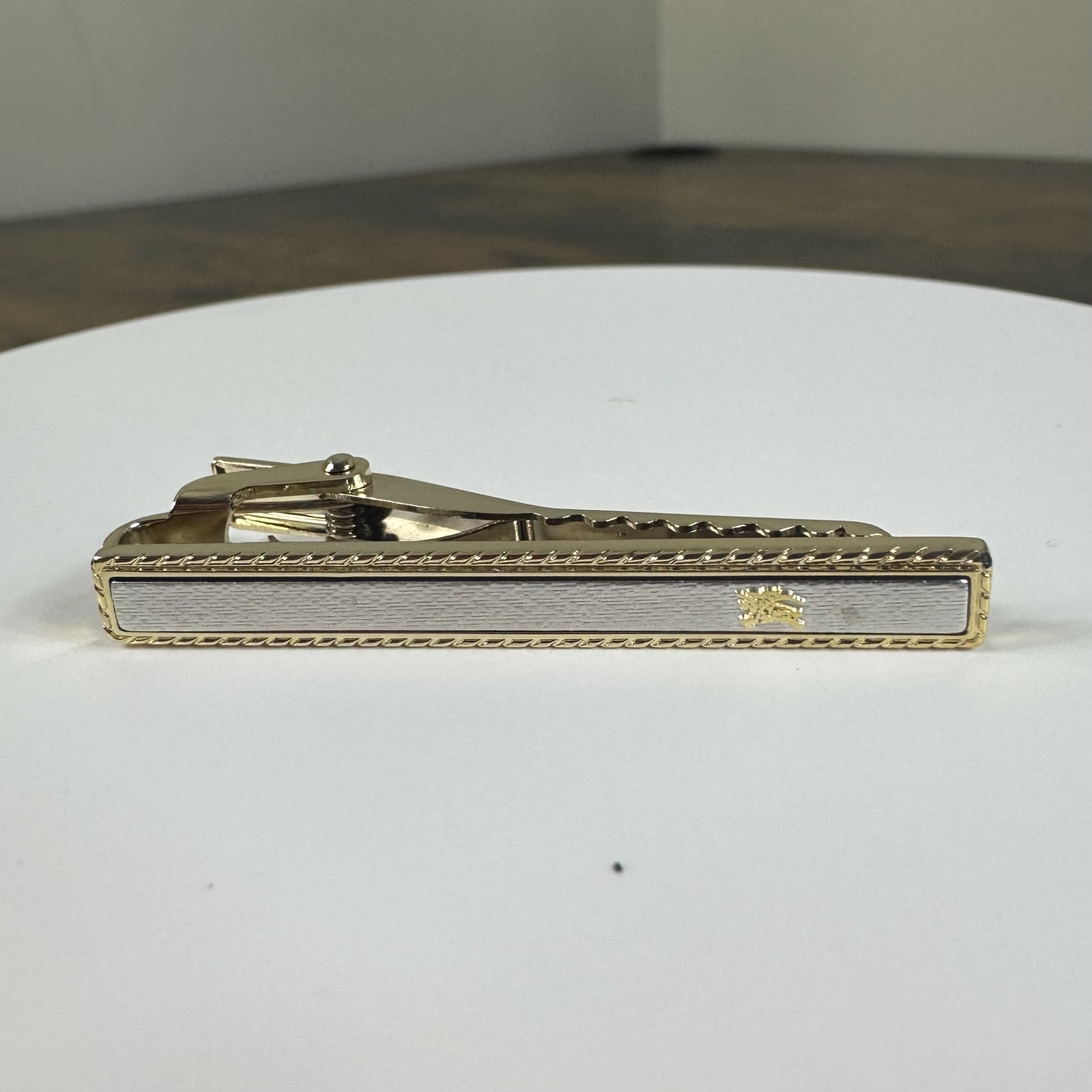Gold-tone Burberry logo tie bar clip on a white background.