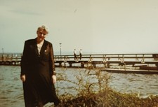 Frau steht im Mantel an Seebrücke Strand altes Farbfoto