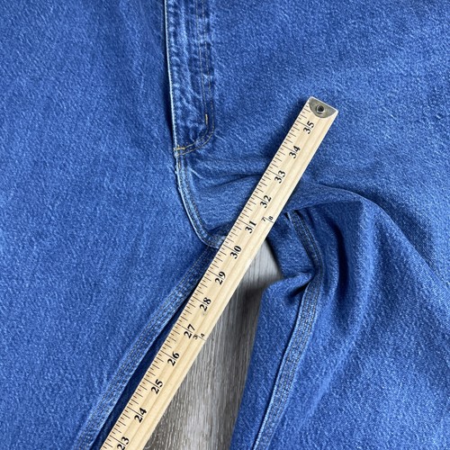 Blue denim Y2K Carhartt men’s carpenter jeans with faded thighs, five-pocket design, and metal rivets, USA Made label visible.