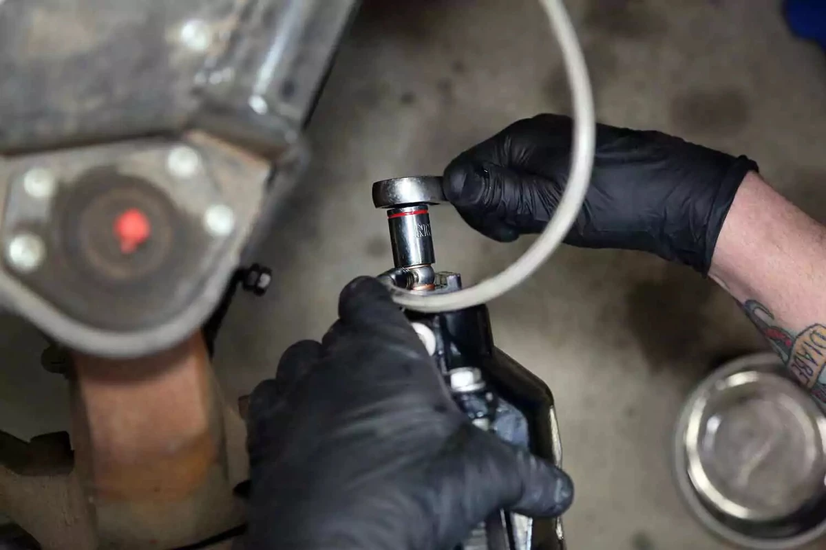 A mechanic tightens the brake line fitting with a ratchet wrench.