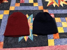 A pair of knitted toddler hats, burgundy and navy, made with acrylic yarn