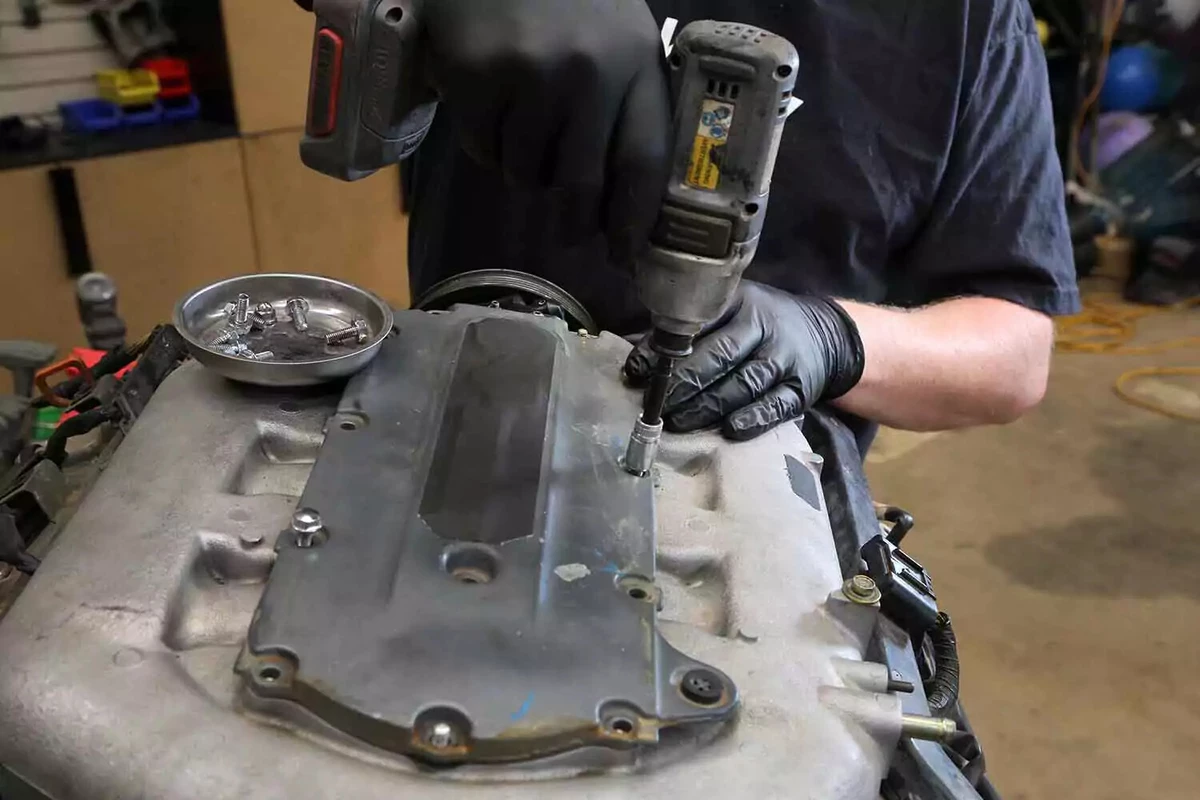 A mechanic reinstalls the upper intake manifold cover with an impact driver.