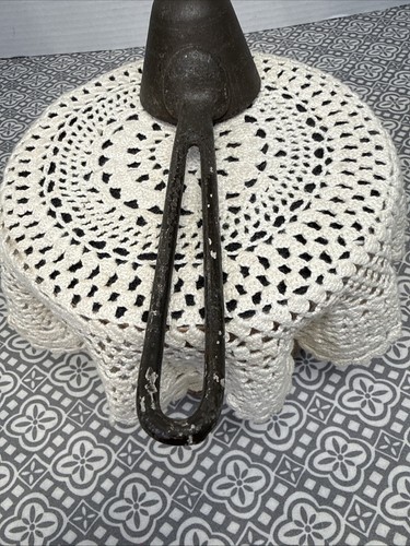 Antique black Gilchrist Turnkey Type ice cream scoop with worn handle, resting on a white crochet-patterned pedestal.