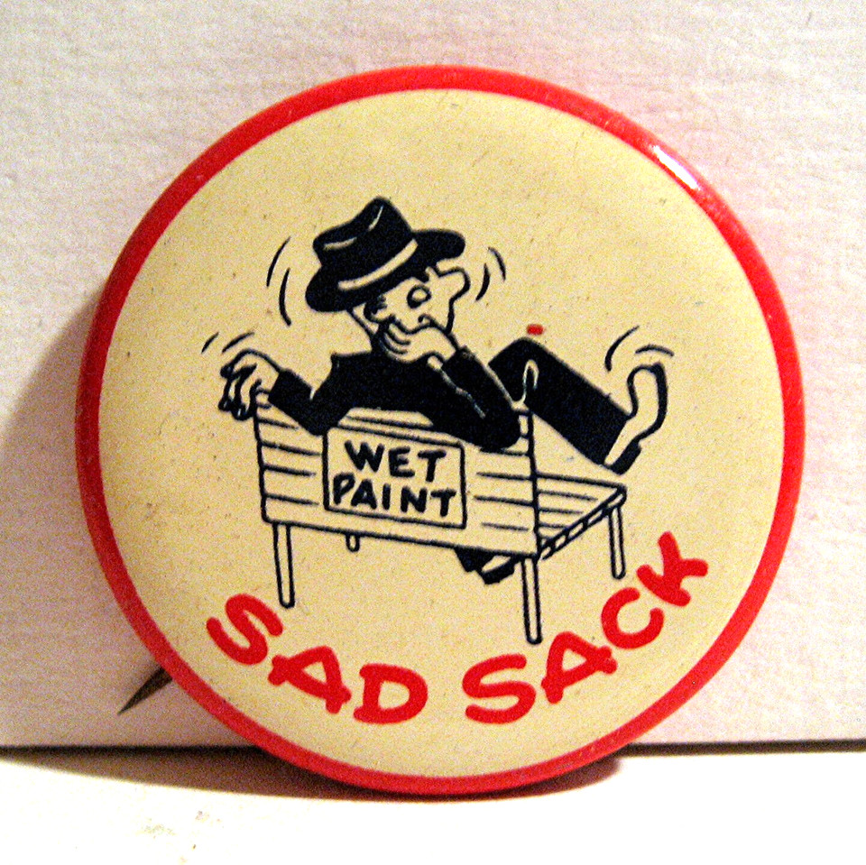 An original old-stock 'Sad Sack' pinback from the 1940s–50s — a relic of the iconic WWII-era comic strip character, still unplayed-with after 70+ years.
