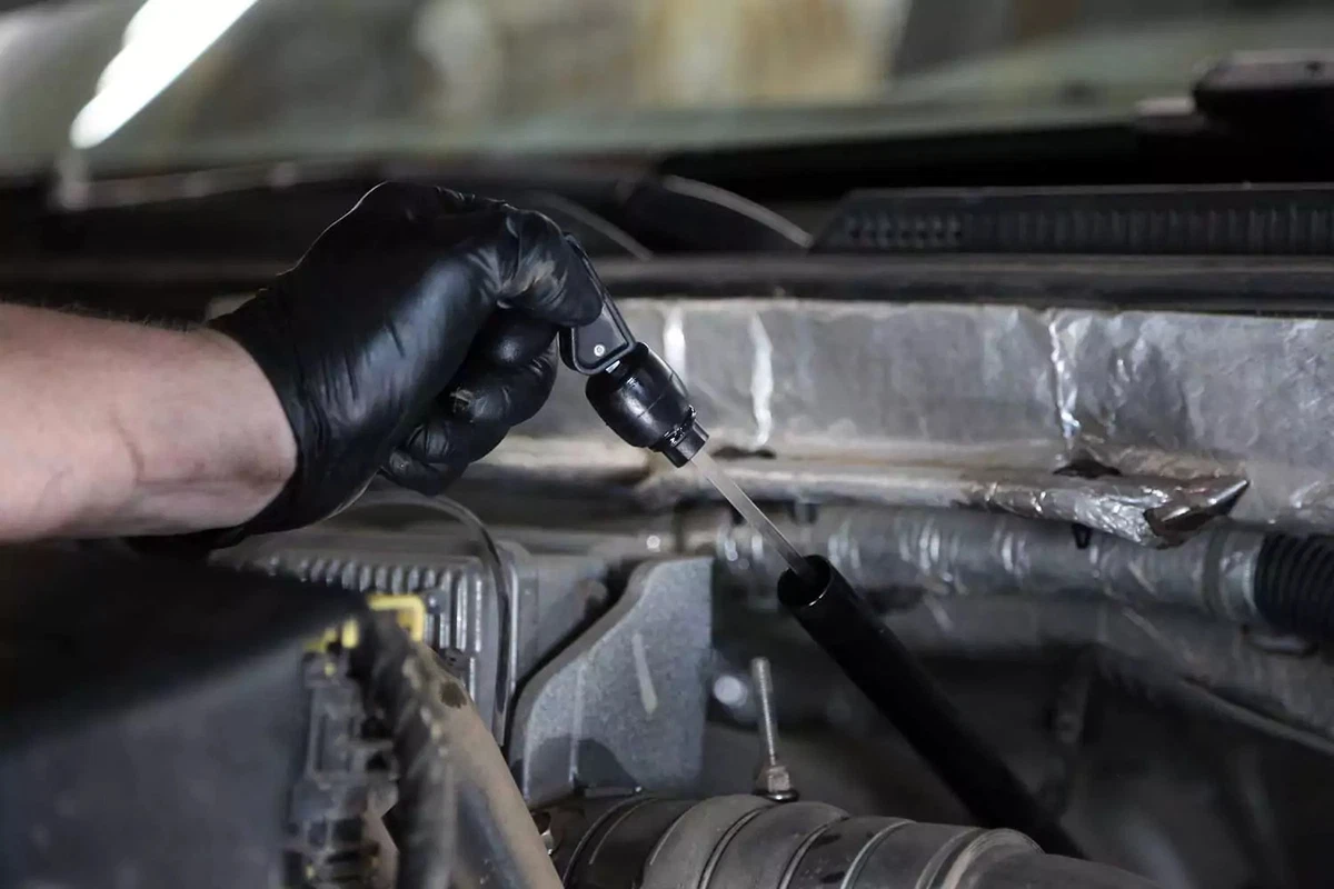 A mechanic removes the dipstick from the automatic transmission’s dipstick tube.