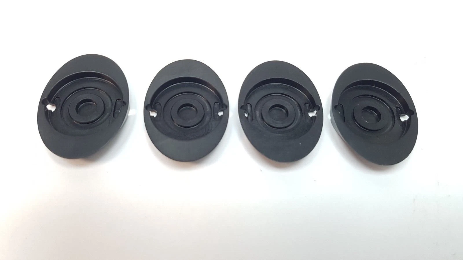 Underside of four MM-1099640 covers with concentric recesses and keyhole slots