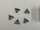 Seven gray TT-221 C2 carbide inserts with triangular black and silver cutting tips, arranged in two rows on a white surface.