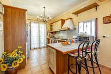 Cucina finta muratura completa di elettrodomestici e sgabelli.