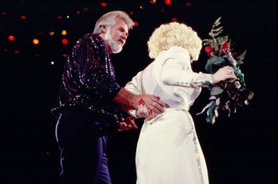 Kenny Rogers escorts Dolly Parton who holds a bouquet of red roses- Old Photo