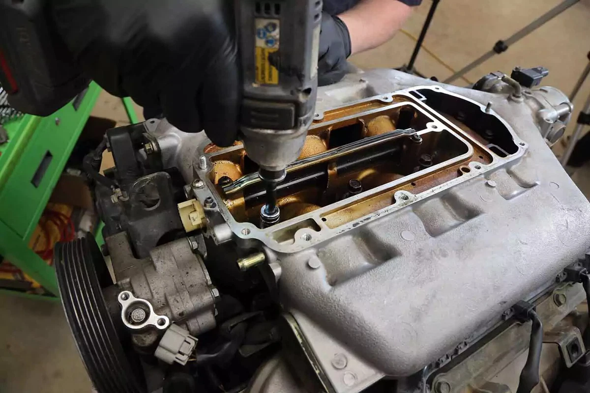 A mechanic removes a main intake bolt with an impact driver.