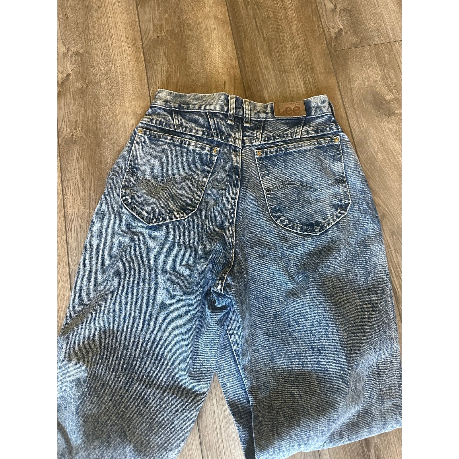 Back view of 90s vintage Lee High Rise Mom Jeans in blue distressed denim with two pockets and visible Lee logo on waistband.