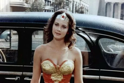 Lynda Carter vollbusig wie eh und je im Wonder Woman Outfit stehend am Auto