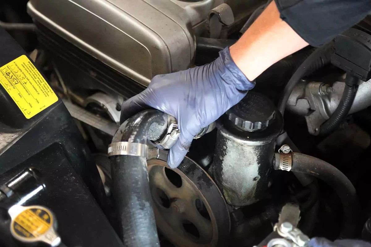 A mechanic removes the upper radiator hose.