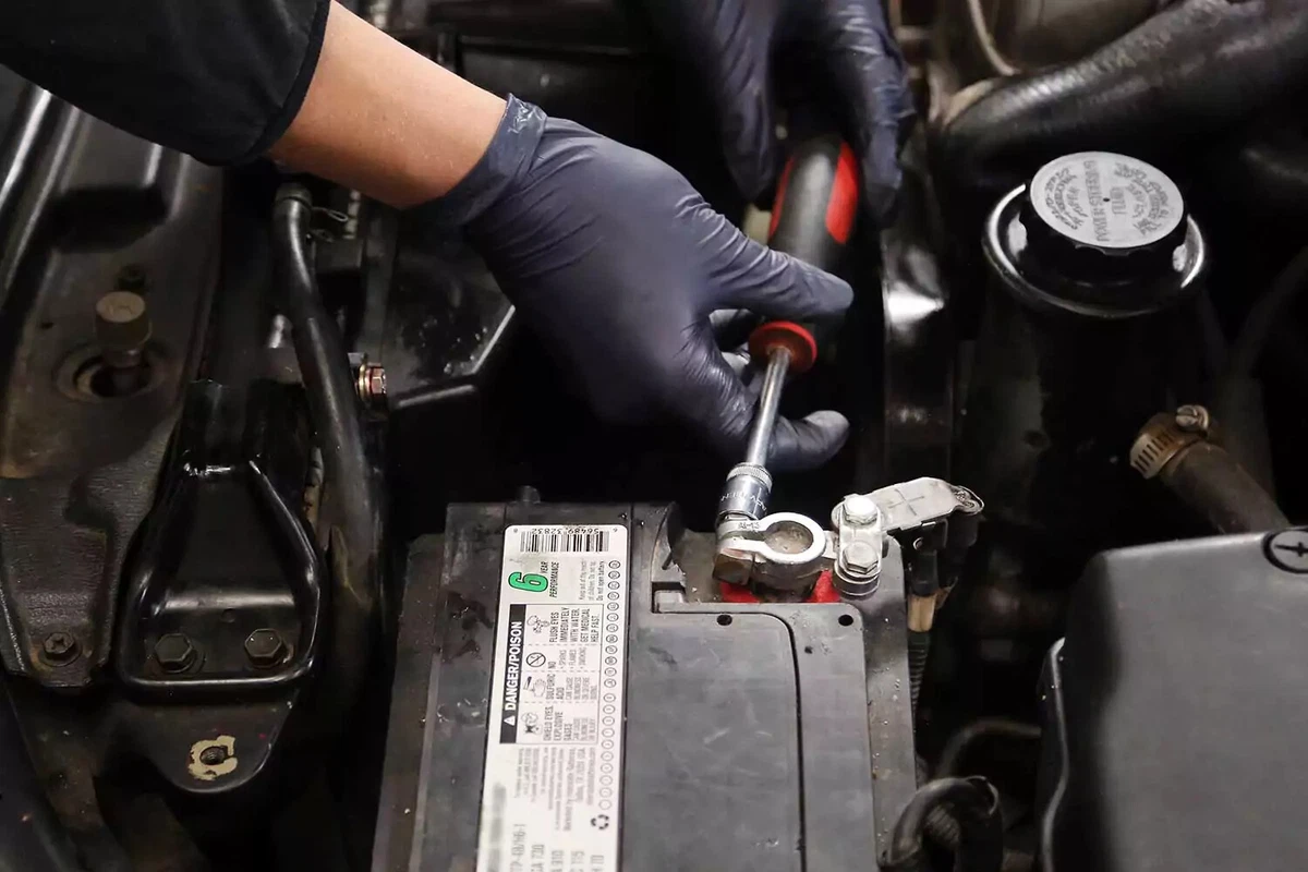 Disconnecting the positive battery terminal with a socket driver.