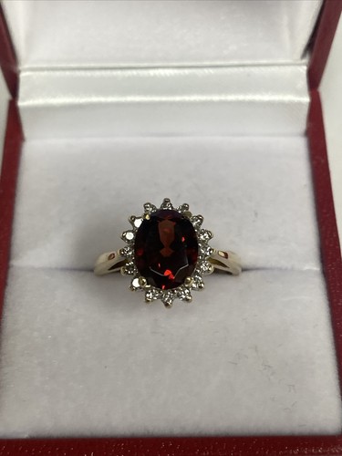 14 Karat Goldring mit einem ovalen Granat umgeben von Diamanten
