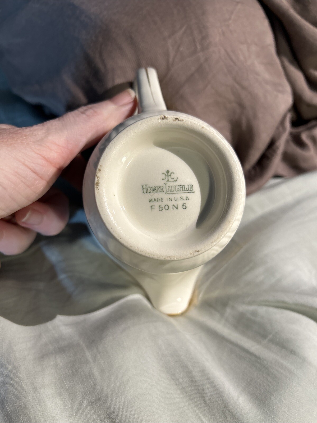 Cream ceramic mug with embossed floral print and “Homer Laughlin Made in U.S.A. F50 N6” on white background.