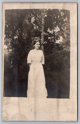 Young Lady among Trees-Long White Dress, Hair Back & Smiling-RPPC Photo Postcard