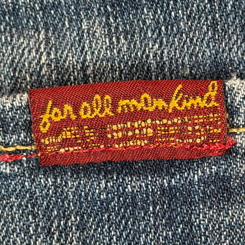 Red fabric tag on 7 For All Mankind denim shorts, size 32, with yellow-edged white text reading “for all mankind.”