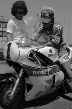Johnny Cecotto stands beside his Yamaha YZR500 as a mechanic sits - Old Photo