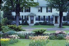 RED BORDER SLIDE White house with a colorful tulip garden and trees.