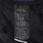 White clothing tag on black fabric with blue ZAINE SW NEOTERIC F0877210 label reading “Made in USA” and product details.